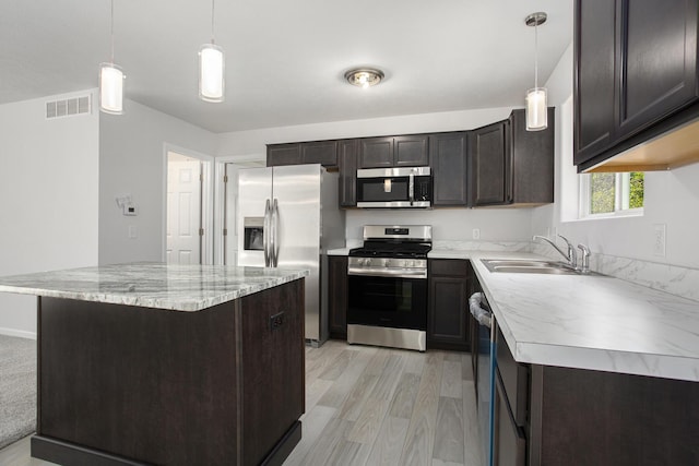 kitchen with a center island, hanging light fixtures, sink, and appliances with stainless steel finishes