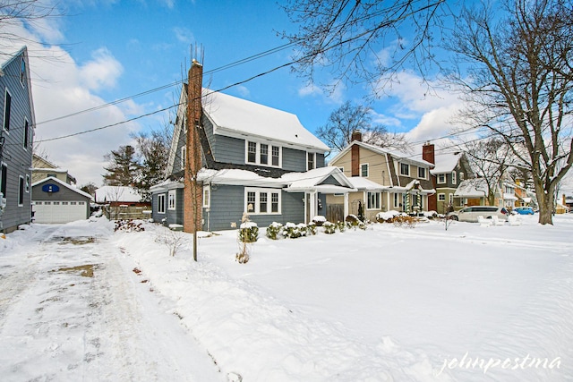 snow covered house with an outbuilding and a garage