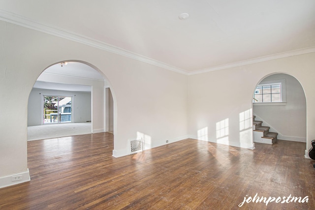 unfurnished living room featuring dark wood-type flooring, ornamental molding, and a wealth of natural light