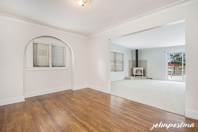 unfurnished living room with hardwood / wood-style flooring, crown molding, and a wood stove