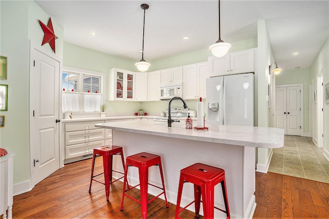 kitchen with a kitchen island with sink, white appliances, and white cabinetry