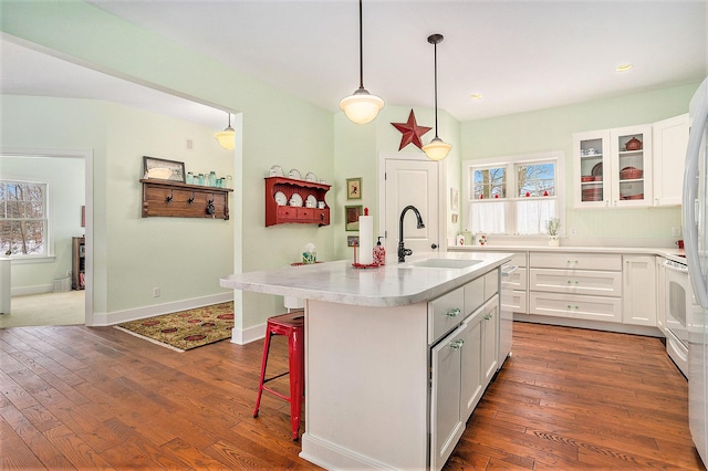 kitchen featuring pendant lighting, sink, a center island with sink, and white cabinets