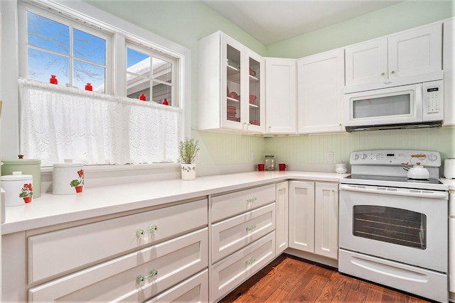 kitchen with dark wood-type flooring, white cabinets, and white appliances