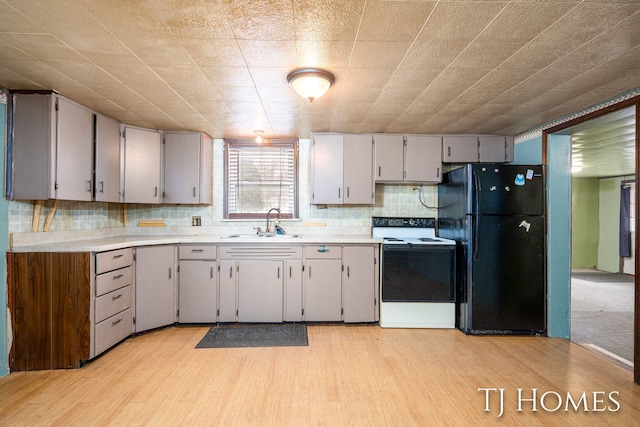 kitchen featuring sink, gray cabinetry, black fridge, electric range oven, and light wood-type flooring