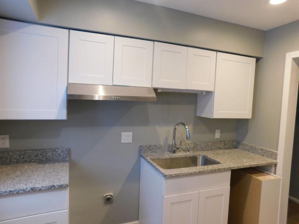 kitchen featuring white cabinetry, sink, and light stone counters