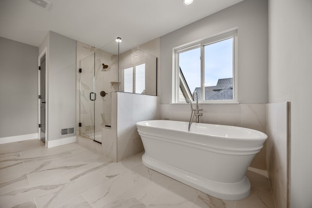 bathroom featuring shower with separate bathtub and tile walls