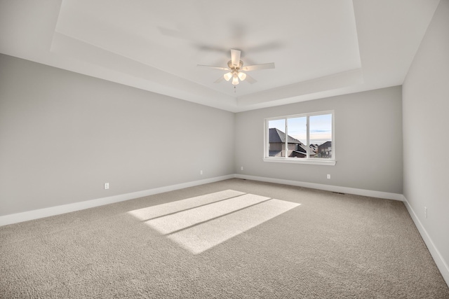 unfurnished room featuring ceiling fan, carpet flooring, and a raised ceiling