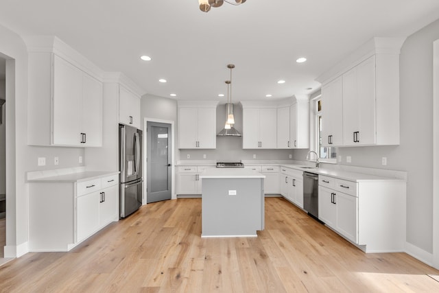 kitchen with white cabinetry, a kitchen island, pendant lighting, stainless steel appliances, and wall chimney range hood