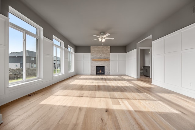 unfurnished living room with ceiling fan, a fireplace, light hardwood / wood-style floors, and a wealth of natural light