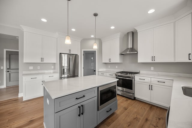 kitchen featuring gray cabinets, stainless steel appliances, light stone counters, white cabinets, and wall chimney exhaust hood