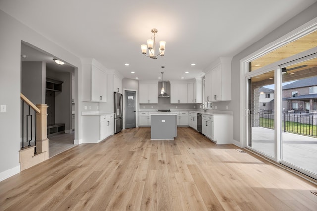 kitchen with decorative light fixtures, a kitchen island, white cabinets, and appliances with stainless steel finishes