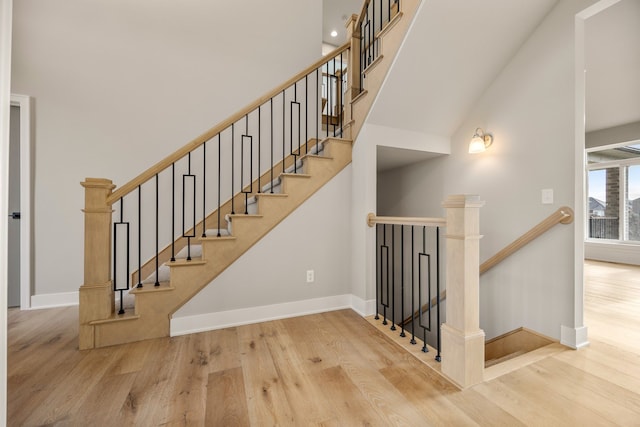 stairs featuring a towering ceiling and hardwood / wood-style floors