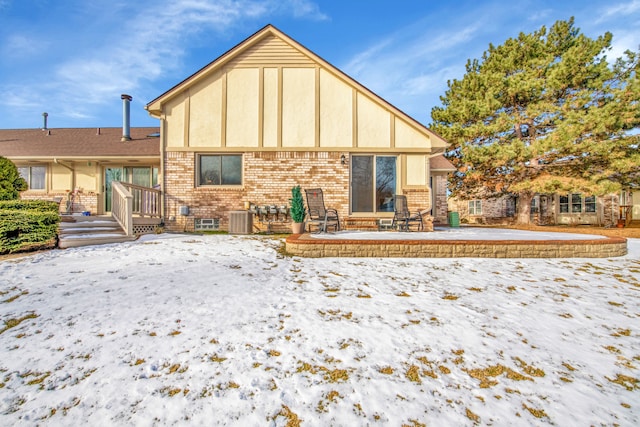 snow covered house with a patio area and central air condition unit