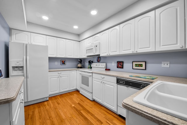 kitchen with sink, white appliances, white cabinets, and light wood-type flooring