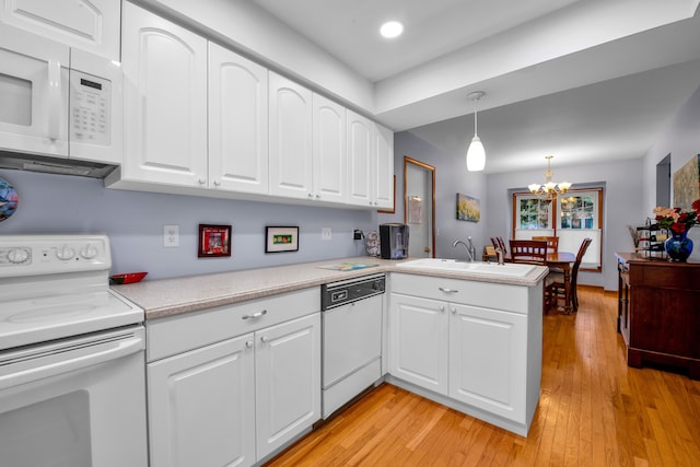 kitchen with sink, white appliances, white cabinetry, decorative light fixtures, and kitchen peninsula