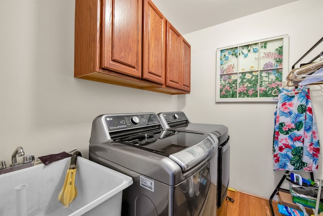 washroom with separate washer and dryer, sink, light hardwood / wood-style flooring, and cabinets