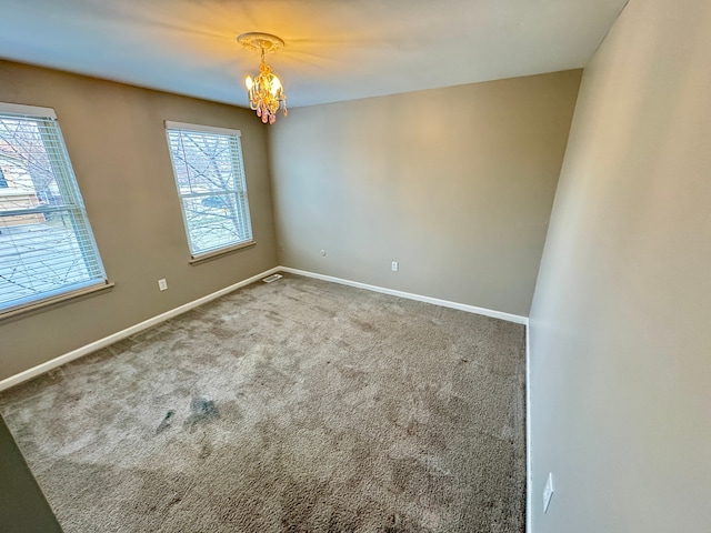 empty room with plenty of natural light, carpet floors, and a notable chandelier