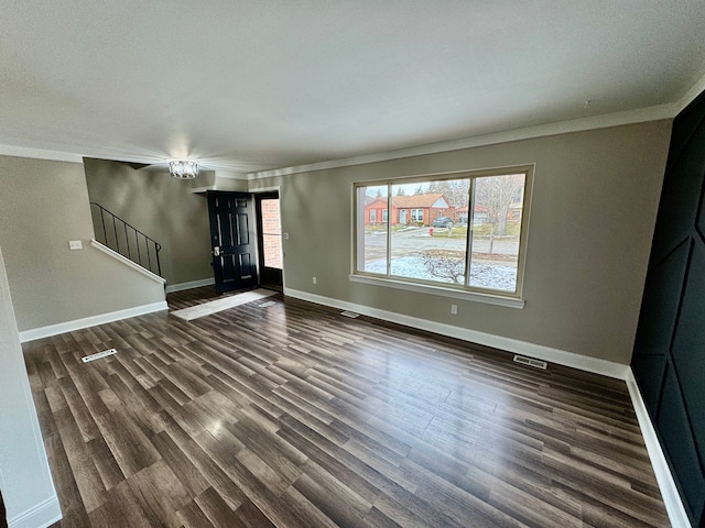 unfurnished living room featuring crown molding and dark hardwood / wood-style floors