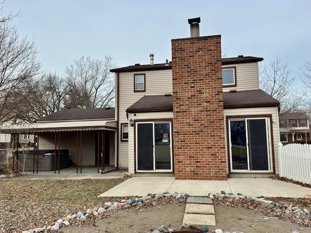 rear view of property with a hot tub and a patio