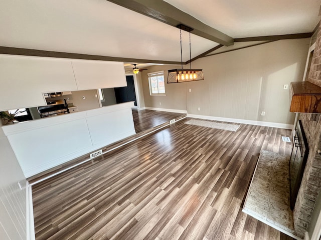 unfurnished living room with hardwood / wood-style flooring, a fireplace, lofted ceiling with beams, and ceiling fan