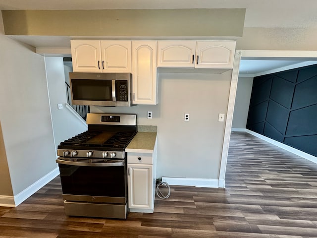 kitchen with dark wood-type flooring, white cabinets, and appliances with stainless steel finishes