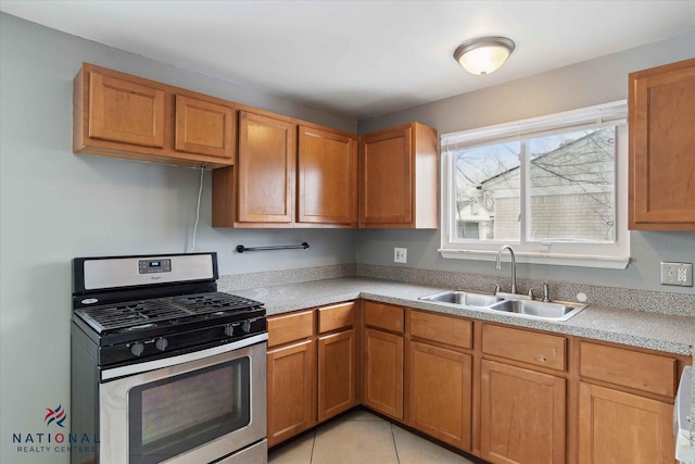 kitchen featuring light tile patterned flooring, stainless steel gas range, and sink