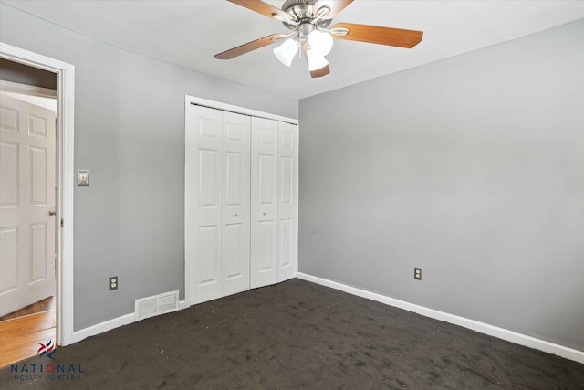 unfurnished bedroom with ceiling fan, dark carpet, and a closet