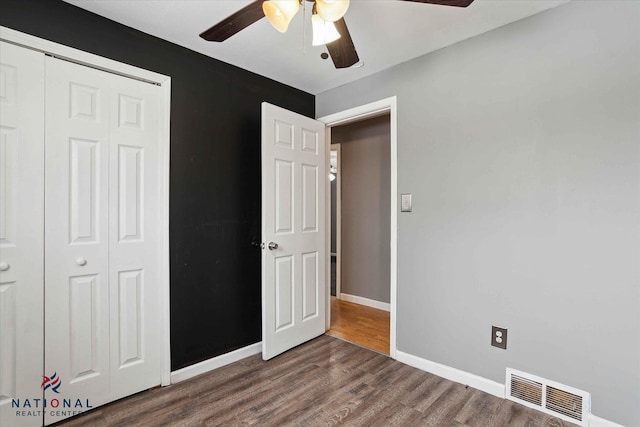 unfurnished bedroom with dark wood-type flooring, a closet, and ceiling fan