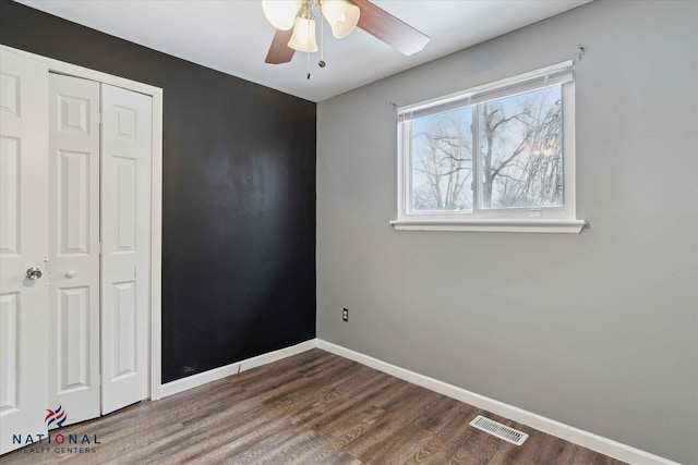 unfurnished bedroom featuring dark hardwood / wood-style flooring, a closet, and ceiling fan