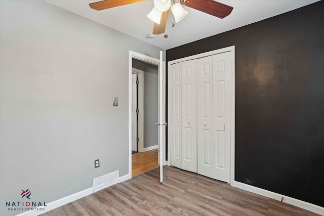 unfurnished bedroom featuring hardwood / wood-style floors, a closet, and ceiling fan