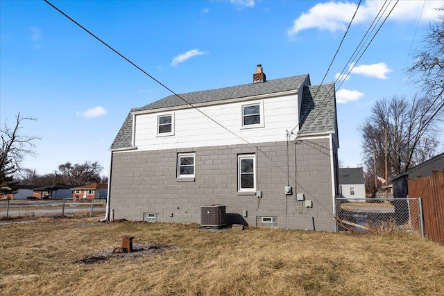 rear view of property featuring central AC and a lawn