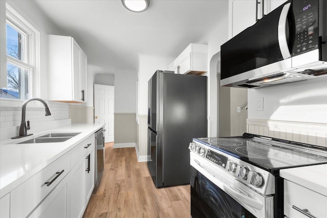 kitchen featuring white cabinetry, sink, light wood-type flooring, and appliances with stainless steel finishes