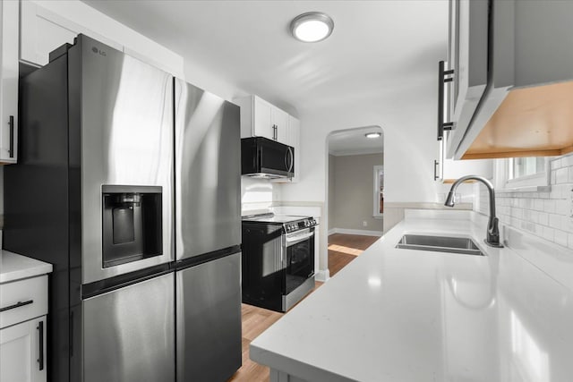 kitchen with sink, light hardwood / wood-style flooring, appliances with stainless steel finishes, tasteful backsplash, and white cabinets