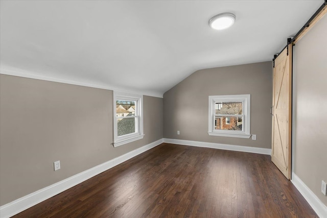 bonus room featuring vaulted ceiling, a barn door, and dark wood-type flooring