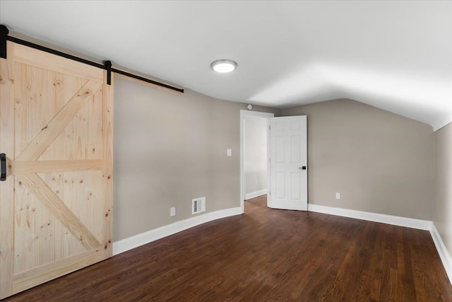 additional living space with lofted ceiling, dark hardwood / wood-style floors, and a barn door