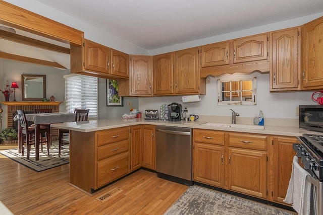 kitchen with appliances with stainless steel finishes, sink, light wood-type flooring, and kitchen peninsula