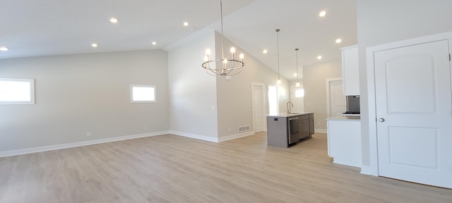 kitchen featuring sink, light hardwood / wood-style flooring, a kitchen island with sink, white cabinets, and decorative light fixtures