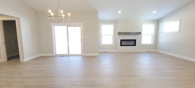 unfurnished living room featuring a notable chandelier, vaulted ceiling, and light hardwood / wood-style floors