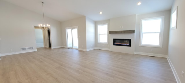 unfurnished living room featuring vaulted ceiling, a chandelier, and light hardwood / wood-style floors