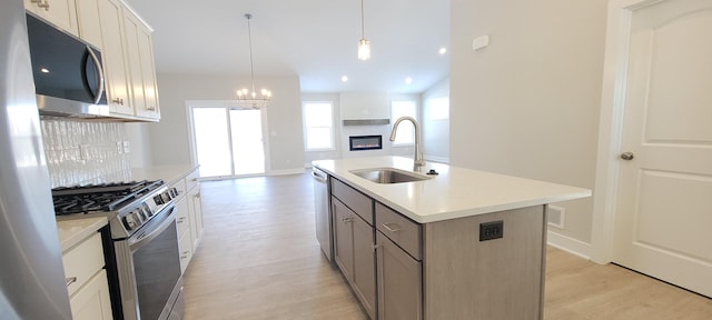 kitchen featuring stainless steel appliances, sink, an island with sink, and white cabinets