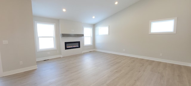 unfurnished living room featuring lofted ceiling and light hardwood / wood-style floors