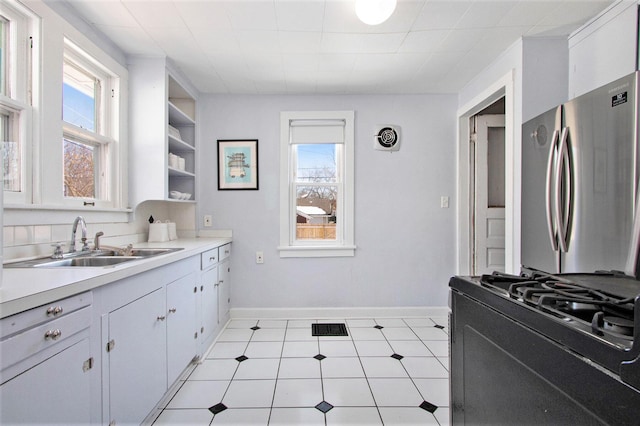 kitchen featuring a healthy amount of sunlight, stainless steel refrigerator, and white cabinets