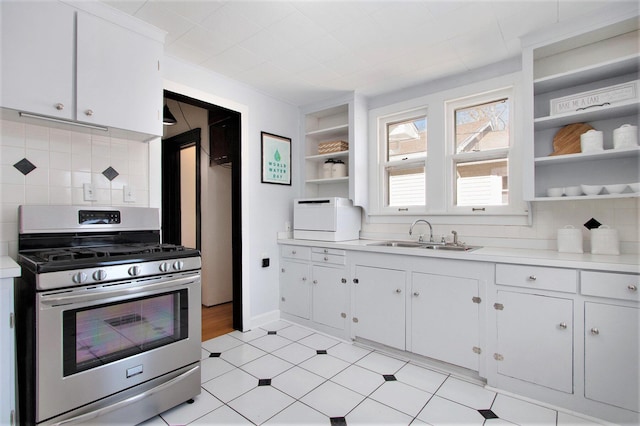 kitchen with sink, white cabinets, backsplash, and stainless steel gas stove