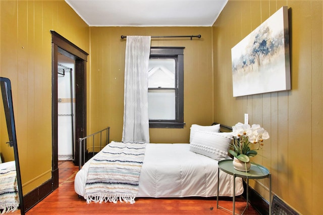 bedroom with wooden walls and hardwood / wood-style floors