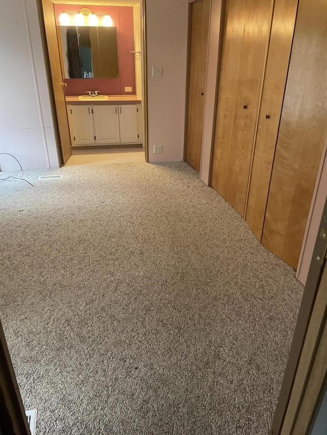 hallway with sink and light colored carpet