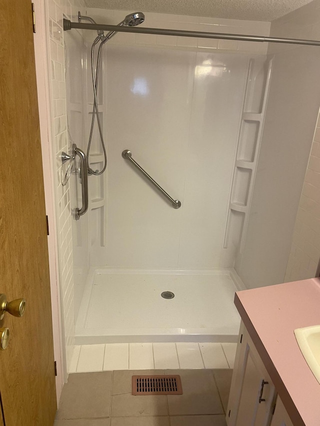 bathroom featuring tile patterned flooring, vanity, a textured ceiling, and walk in shower