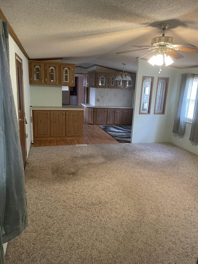 kitchen featuring ceiling fan, dark carpet, hanging light fixtures, and a textured ceiling