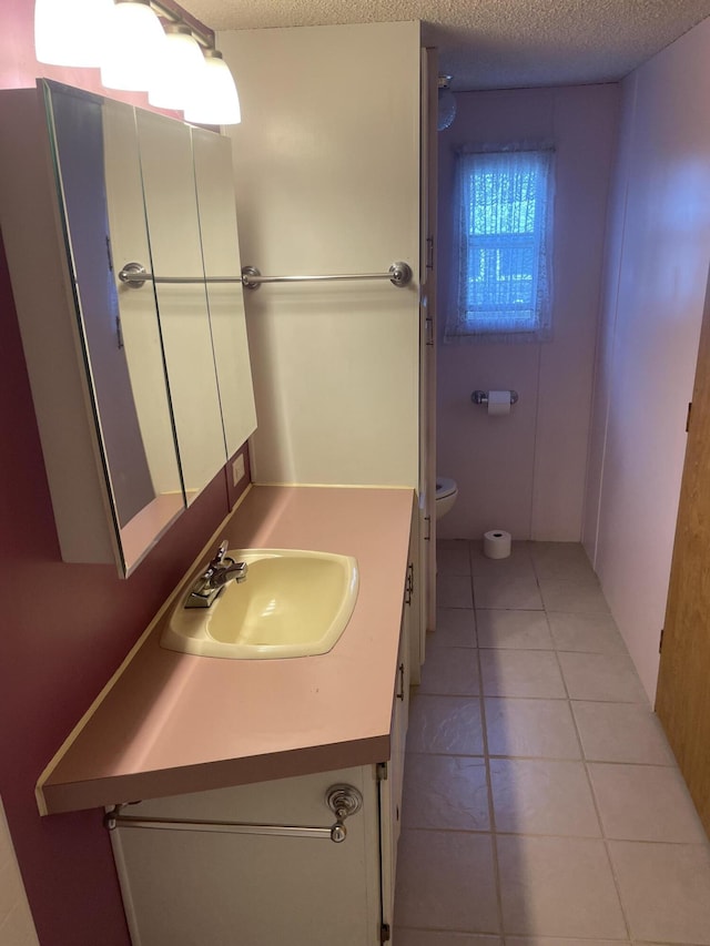 bathroom featuring vanity, tile patterned flooring, toilet, and a textured ceiling