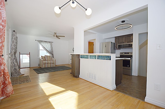 kitchen with ceiling fan, dark brown cabinetry, stainless steel appliances, and light wood-type flooring