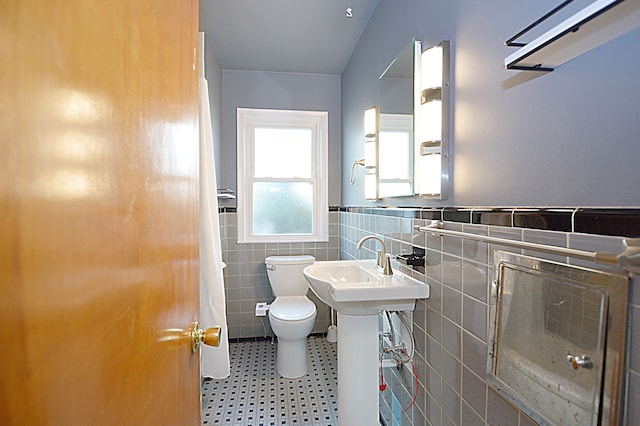 bathroom featuring tile walls and toilet